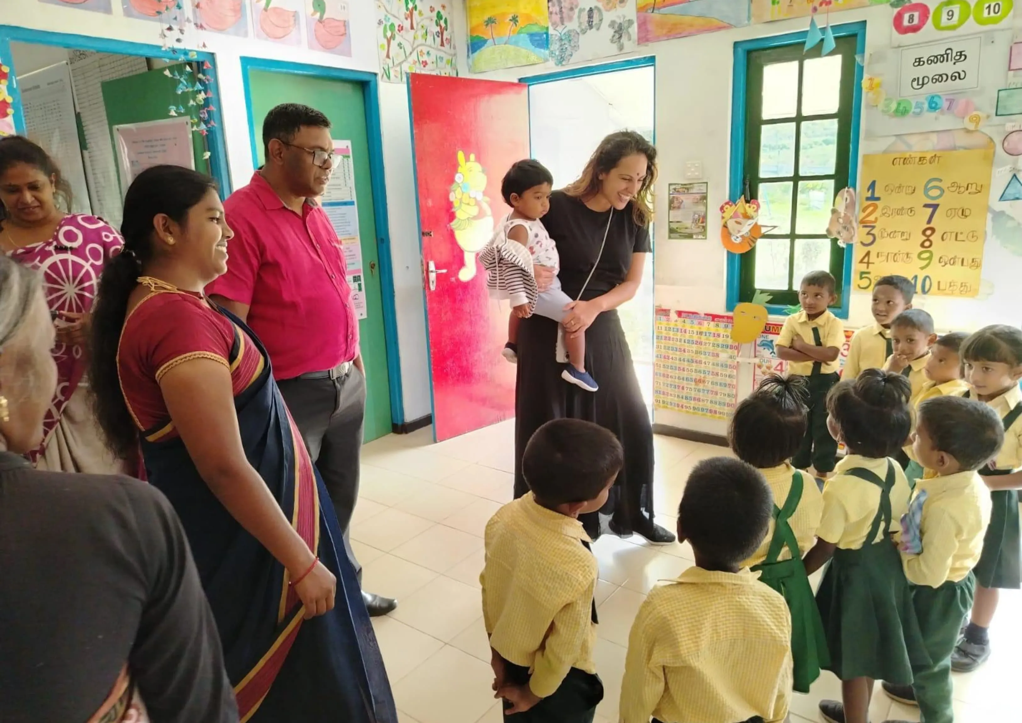 A volunteer greeting schoolchildren in a community classroom.